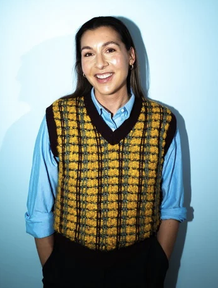 A grown woman smiling with her hands in her pockets.