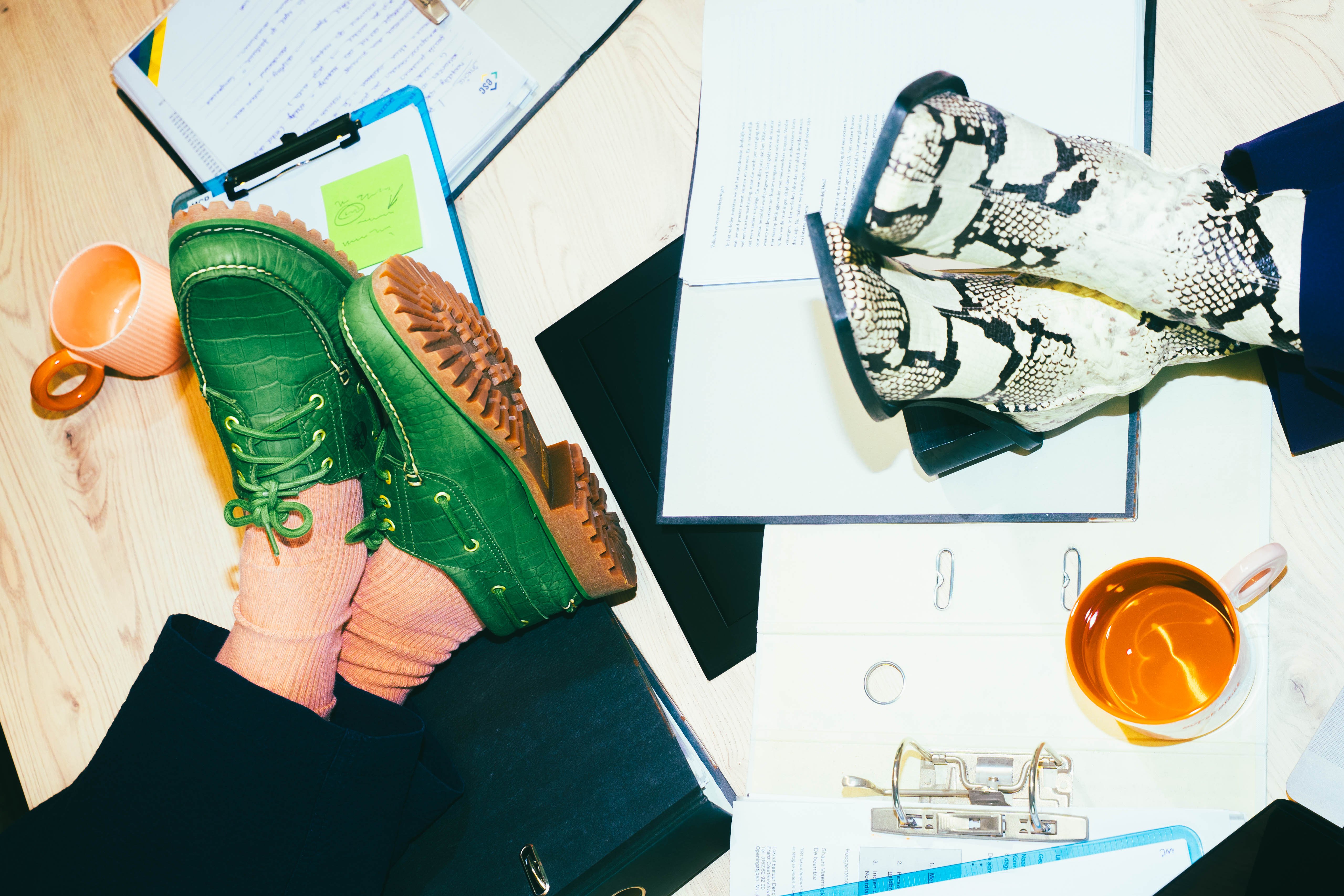 Two people sitting with their shoes on a desk.