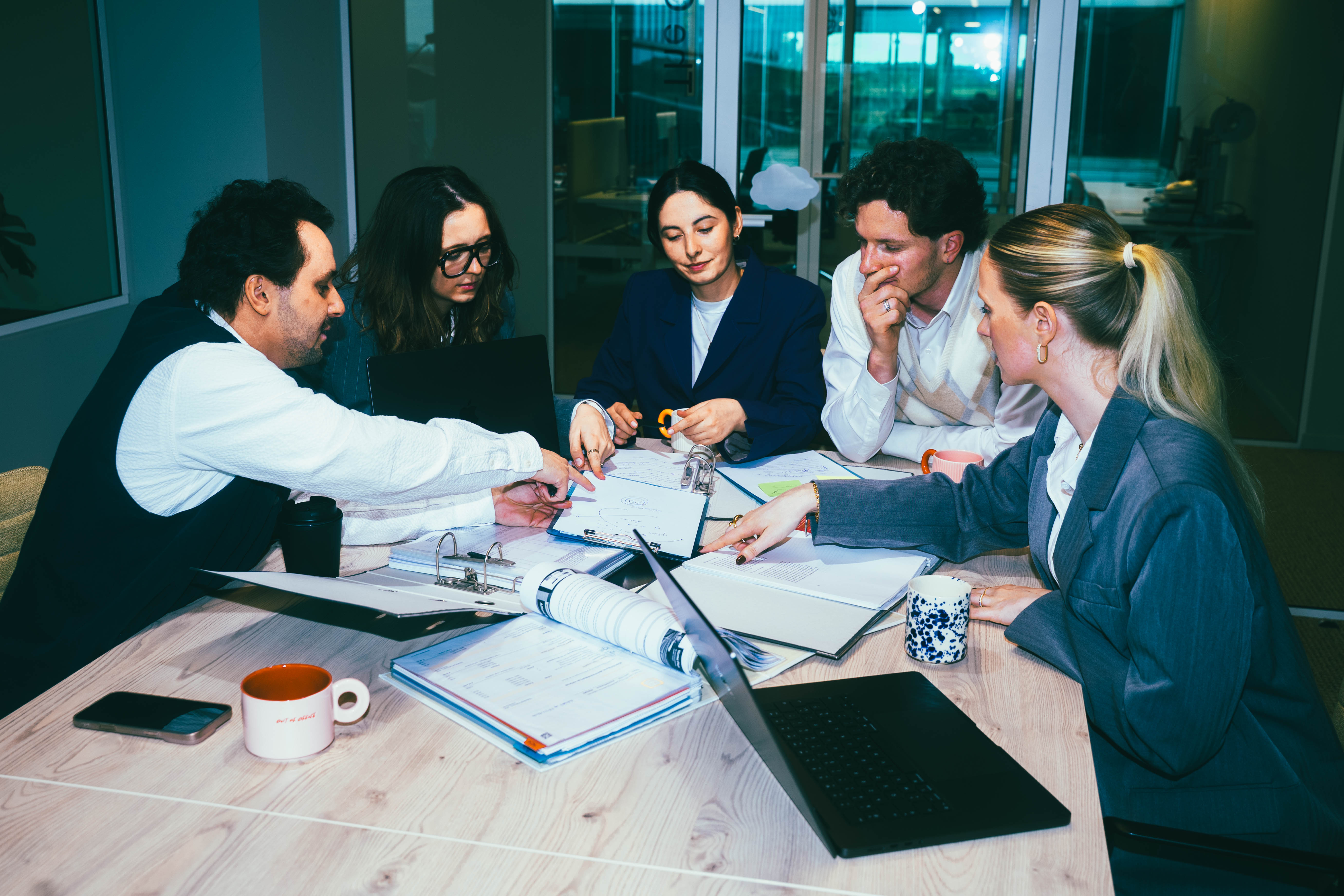 PEOPLE SITTING AROUND TABLE IN A MEETING