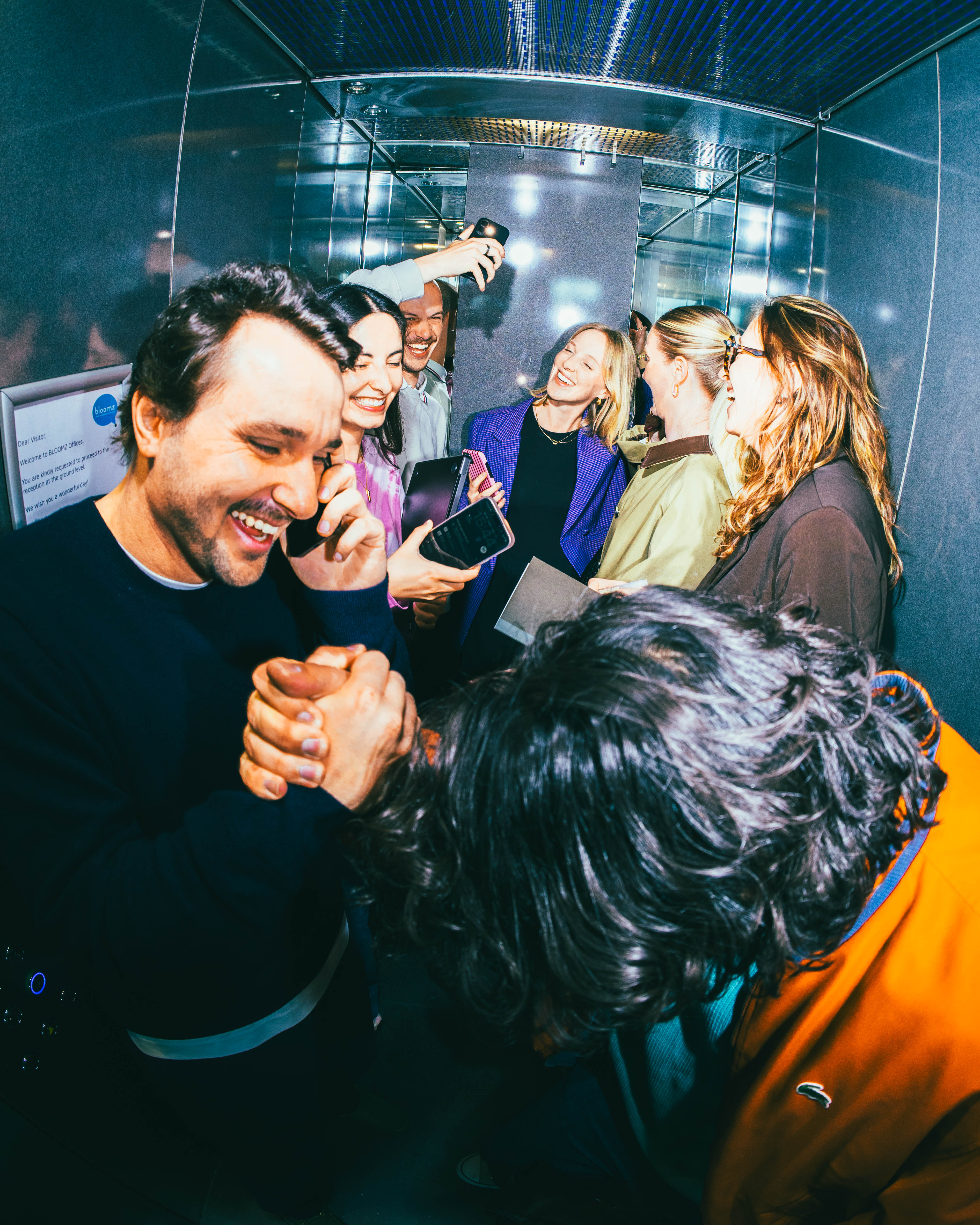 PEOPLE IN ELEVATOR DOING A HANDSHAKE