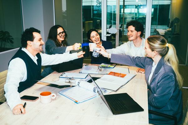 A team at the office toasting with their coffee mugs.