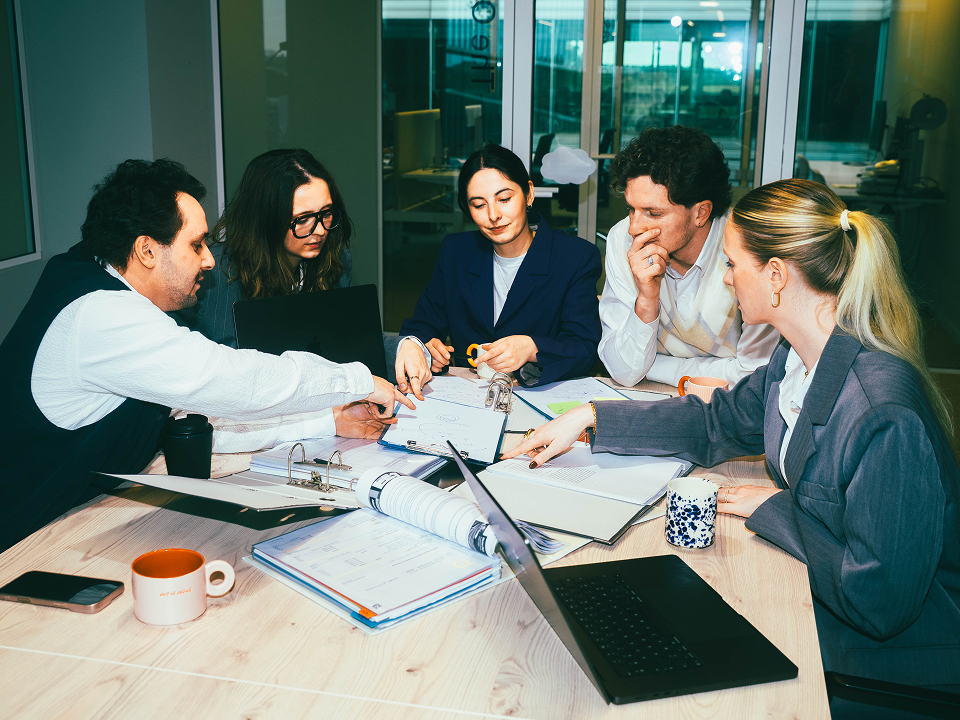 A young team surrounded at a meeting table having a conversation.