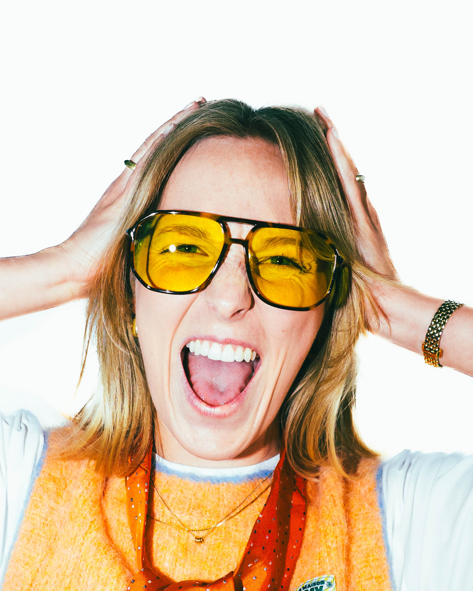 A young woman laughing and screaming while keeping her hands against her head.
