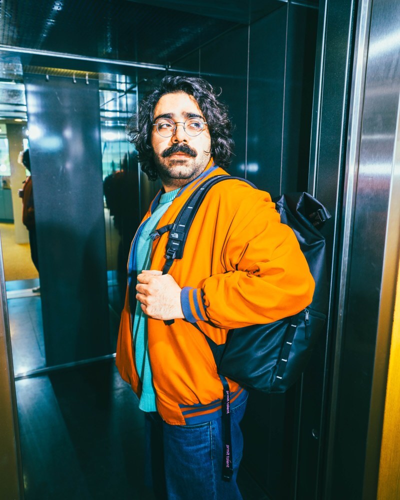 Young man going into an elevator with a backpack on.